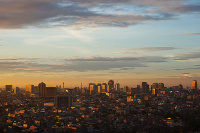 Modern buildings in city against sky during sunset