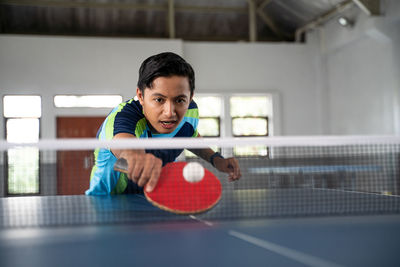 Young man playing with ball on tennis