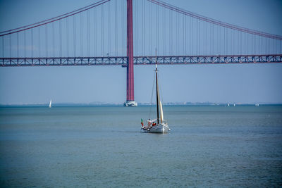 Boat sailing towards april 25th bridge over tagus river