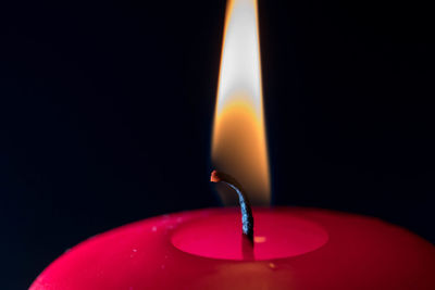 Close-up of lit candle against black background