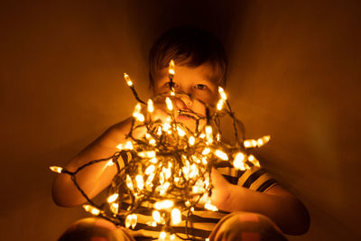 Full length of boy with illuminated lights at home