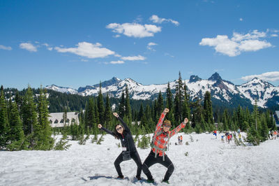 Panoramic view of people on snowy field against sky