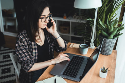 Young woman talking on the phone in her home office. work from home concept