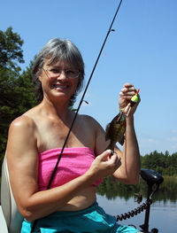 Portrait of senior woman holding fish on fishing line