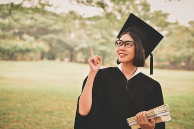 Young woman in graduation gown holding books