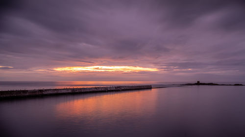 Scenic view of sea against dramatic sky during sunset