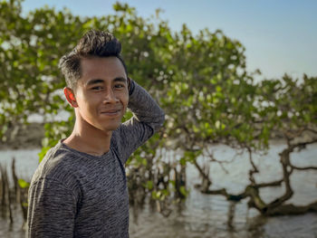 Portrait of young man standing against plants