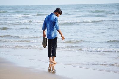 Rear view full length of man standing on shore at beach