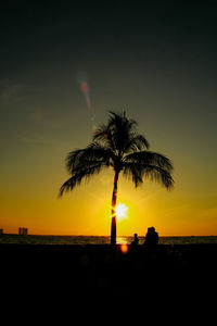 Silhouette palm tree by sea against sky during sunset