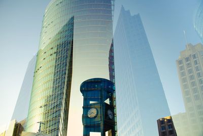 Double exposure of clock tower and modern buildings against clear sky in city