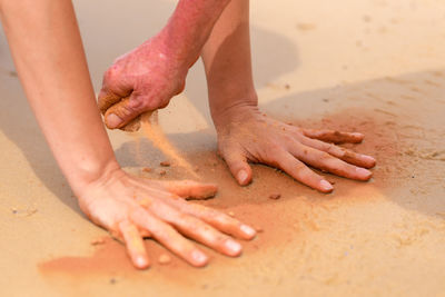 Cropped image of hands playing with sand at beach