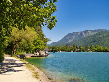 Scenic view of sea and mountains against clear blue sky