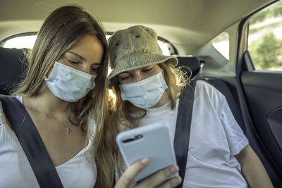 Portrait of young woman using smart phone in car