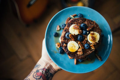 Cropped hand with tattoos holding pancakes