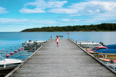 People on pier over sea against sky