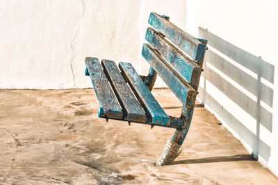 High angle view of empty bench against wall