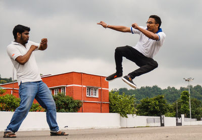 Young man looking at friend jumping in mid-air over street