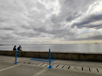 People looking at sea against sky