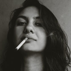 Close-up portrait of young woman smoking cigarette