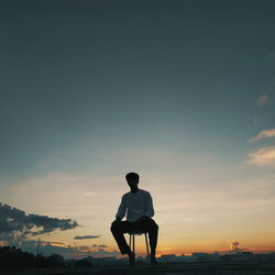 Full length of silhouette man sitting against sky during sunset