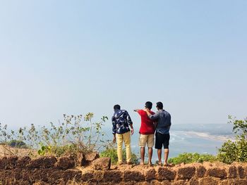 Rear view of people standing on fort against sky