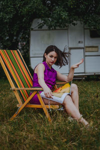 Young woman sitting on seat in yard