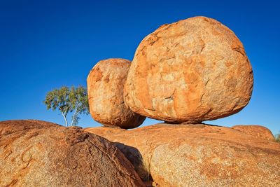 Low angle view of devils marbles rock formation against clear blue sky