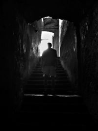 Full length rear view of woman standing in tunnel