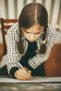 Close-up of a girl looking down while sitting on table