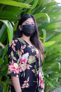 Portrait of young woman standing against plants