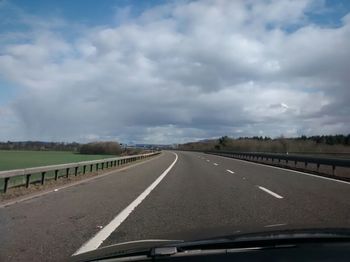 Country road against cloudy sky