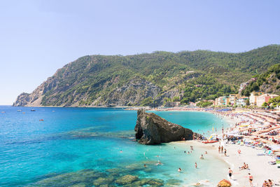 Touristic beach in front of tree covered hills