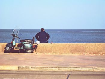 People sitting on beach against clear sky