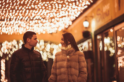 Friends standing against illuminated wall