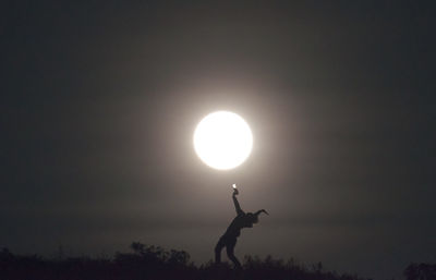 Silhouette person against bright sun at sunset