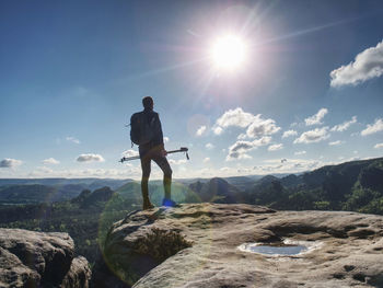 Man in sports clothes with walking sticks on mountain near edge. trekking sticks for nordic walking