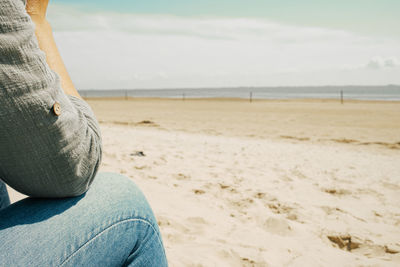 Low section of woman sitting at beach