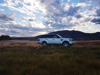 Car parked on field against sky