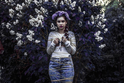 Young woman standing against plants