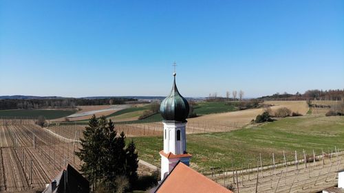 Traditional windmill on field against clear blue sky