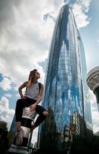 Low angle view of woman against building in city