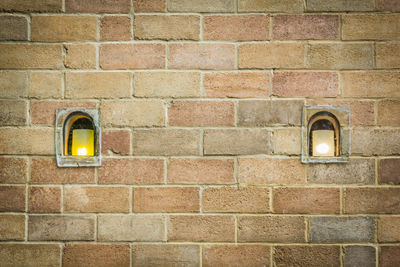 Illuminated lamp on brick wall