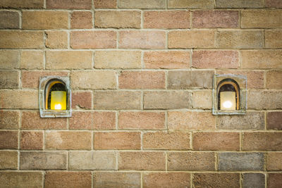 Illuminated lamp on brick wall