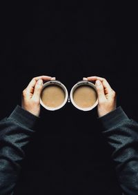 Close-up of hand holding drink over black background