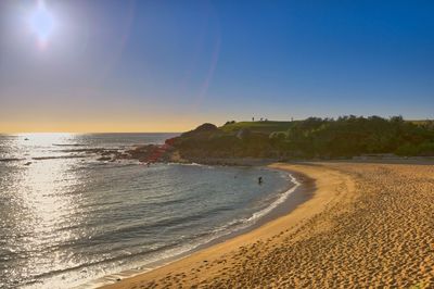 Scenic view of beach against clear sky during sunset