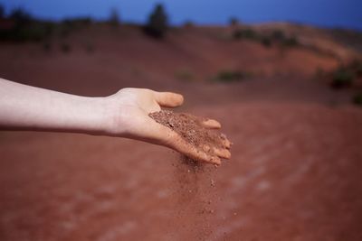 Cropped hand of woman holding sand in hand outdoors