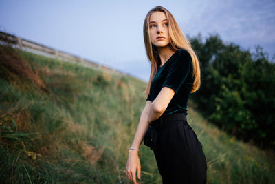 Beautiful young woman standing on land against sky