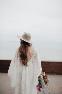 Bride standing on boardwalk against sky
