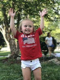 Full length of a smiling girl standing on grass