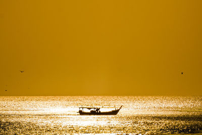 Silhouette boat in sea against orange sky